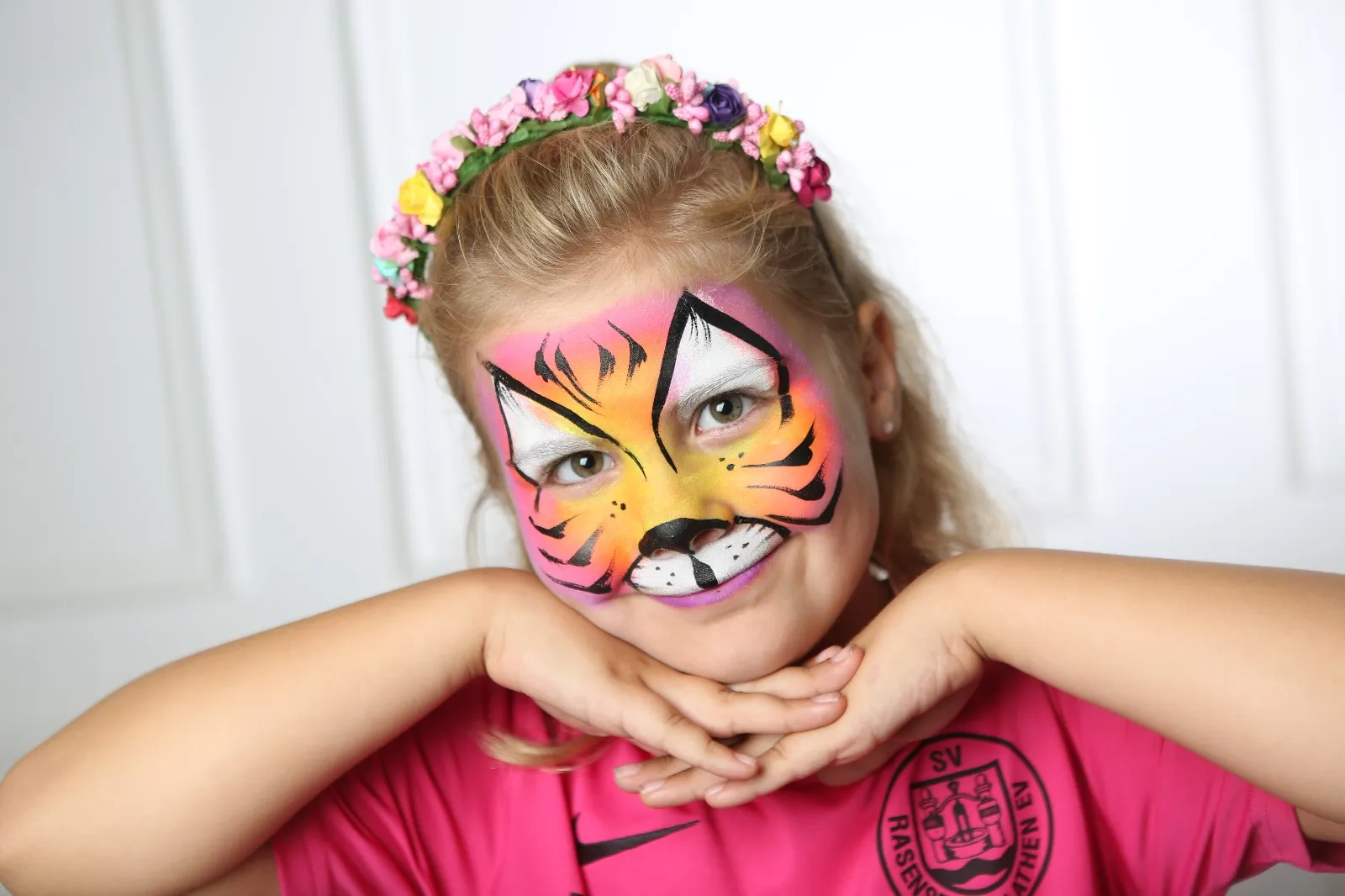 Mädchen mit Blumenkranz und als Tiger geschminktem Gesicht