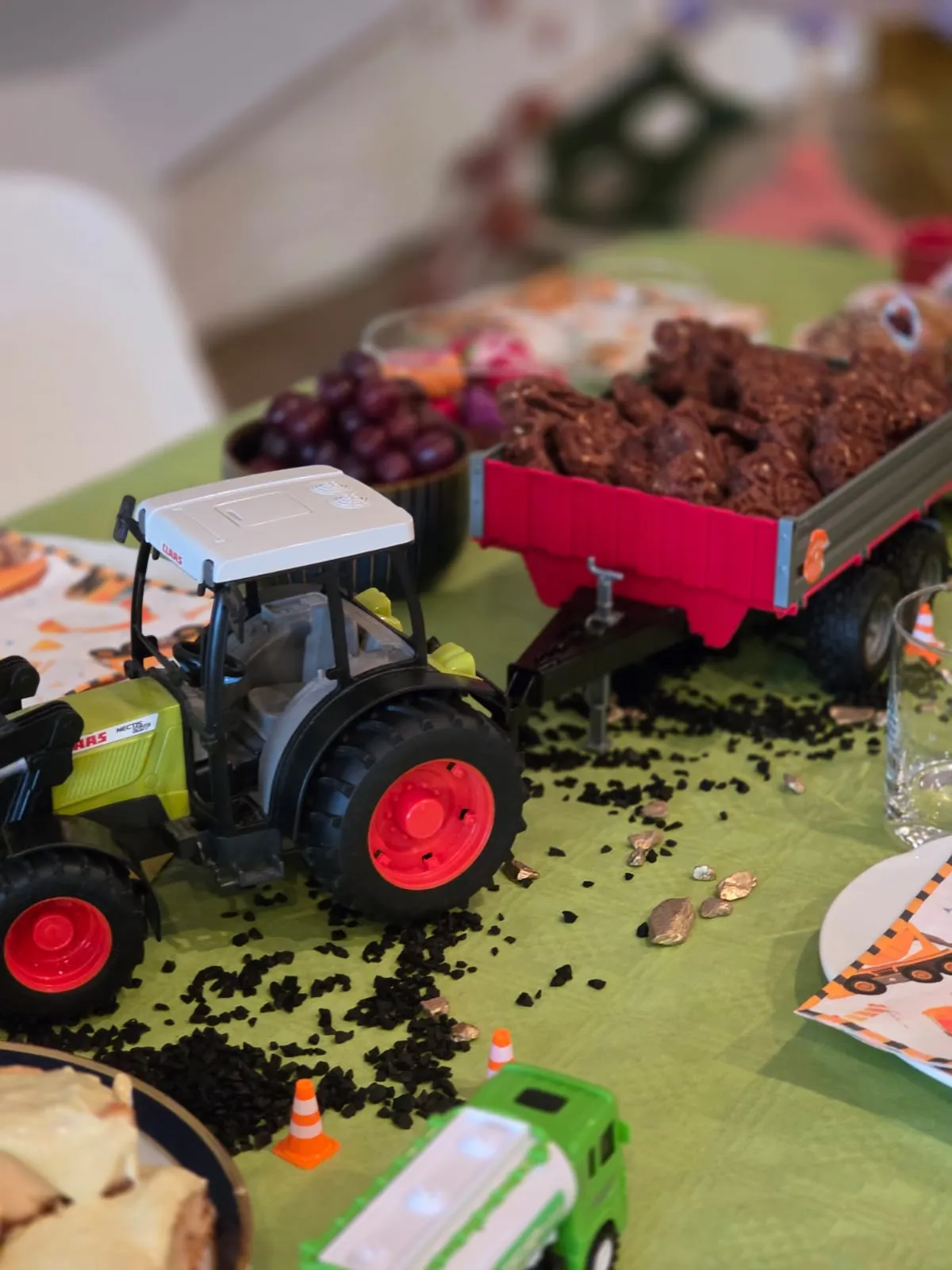 Spielzeugtraktor mit Anhänger voller Schokokuchen auf dem Traktor-Geburtstagstisch